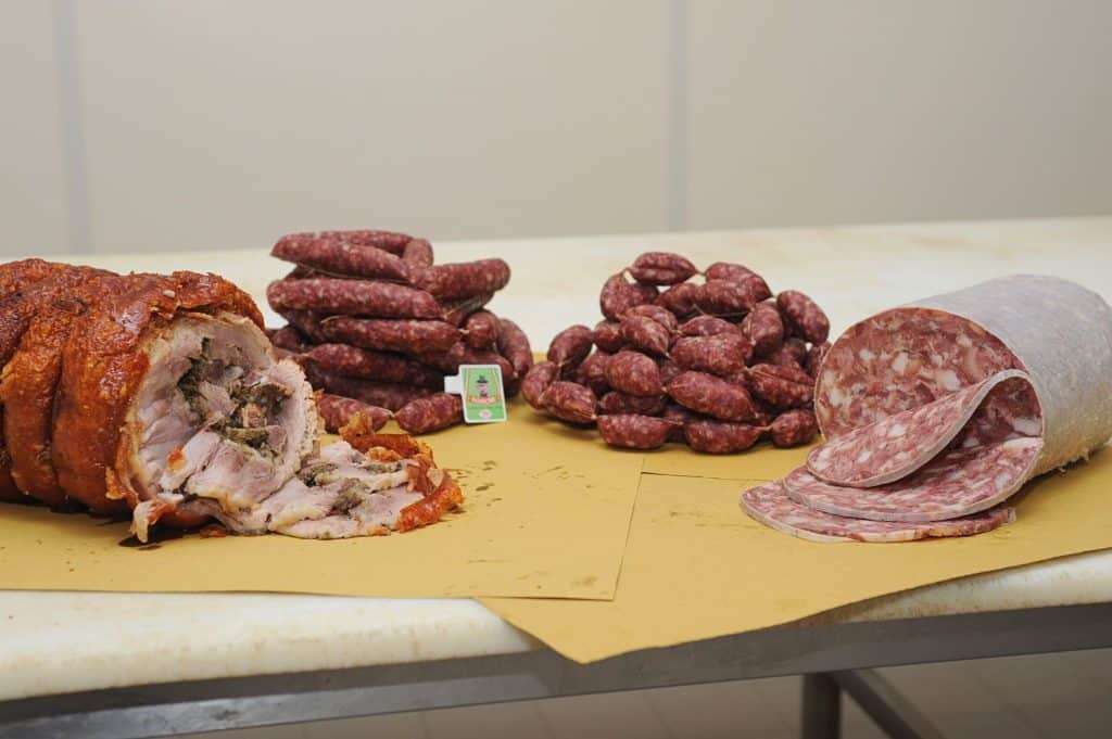 Porchetta, salsicce e salame su tavolo.