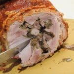 Porchetta affettata su tagliere di legno.