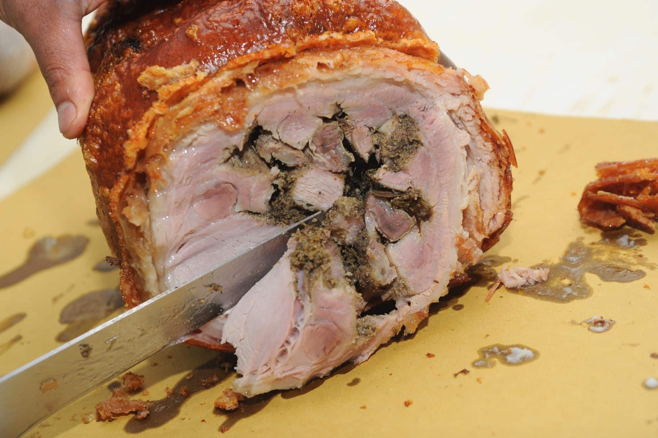 Porchetta affettata su tagliere di legno.